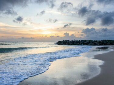 Strand mit Wellen und Abendhimmel Strand mit Wellen, Steinen und einem Abendhimmel, der eine ruhige Atmosphäre schafft.